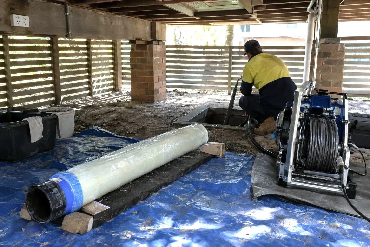 Pipe relining equipment on a drop sheet near an access pit